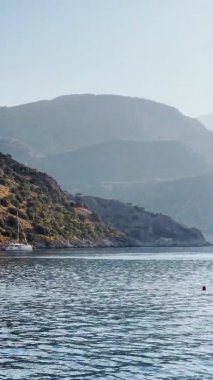 Türkiye, Gemiler, 06 Ekim 2021: Marmaris yakınlarındaki bir çok adanın yakınlarındaki Gemiler Körfezi, yelkenli yarışlarına katılanlar kıyı şeridinde, pek çok direkte, arka planda dağlar