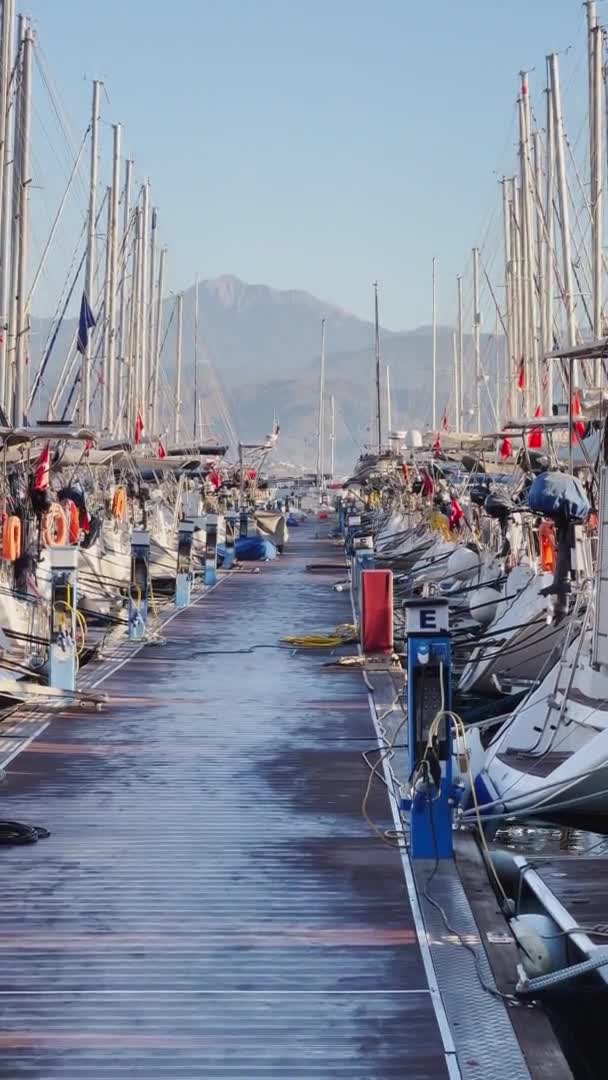 Turquia, Fethiye, 06 de outubro de 2021: Porto de iate com muitos veleiros pela manhã, muitos mastros, cais sem pessoas, tempo ensolarado, montanhas no horizonte — Vídeo de Stock