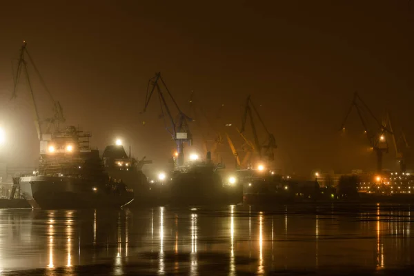 Russia, St. Petersburg, 05 February 2021: The construction of nuclear icebreakers, cranes of of the Baltic shipyard in a frosty winter evening, steam over the Neva river, smooth surface of the river — Stock Photo, Image
