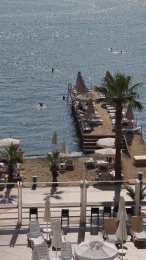 Türkiye, Marmaris, 02 Ekim 2021: Tatil beldesinin güvertesinde güneşli iskelede güneşlenen insanlar, güneşli havalarda, salgın ve kumlu plajlarda ve palmiye ağaçlarında tatillerini geçiriyorlar