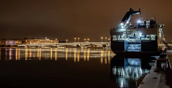 Saint-Petersburg kış gecesinin panoramik görüntüleri. Suya yansıyan muhteşem görüntüler. Blagoveshchensky köprüsü ya da Teğmen Schmidt, Isaac katedrali yakınlarında demirlemiş büyük bir gemi. — Stok fotoğraf