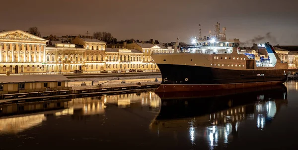 As imagens panorâmicas da cidade noturna de inverno São Petersburgo com reflexão pitoresca sobre a água, grande navio atracado perto da ponte Blagoveshchensky ou tenente Schmidt, catedral Isaac no fundo — Fotografia de Stock