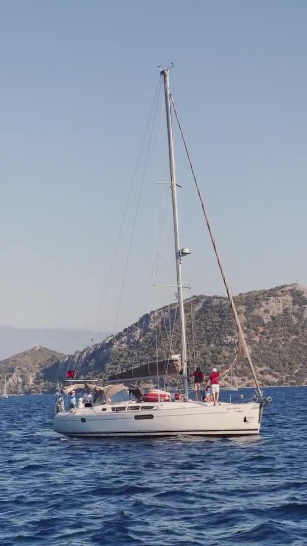 Turquia, Fethiye, 03 de outubro de 2021: A pitoresca baía de Sarsala, perto de uma das muitas ilhas perto de Marmaris, participantes da regata à vela no barco, montanhas no fundo — Vídeo de Stock
