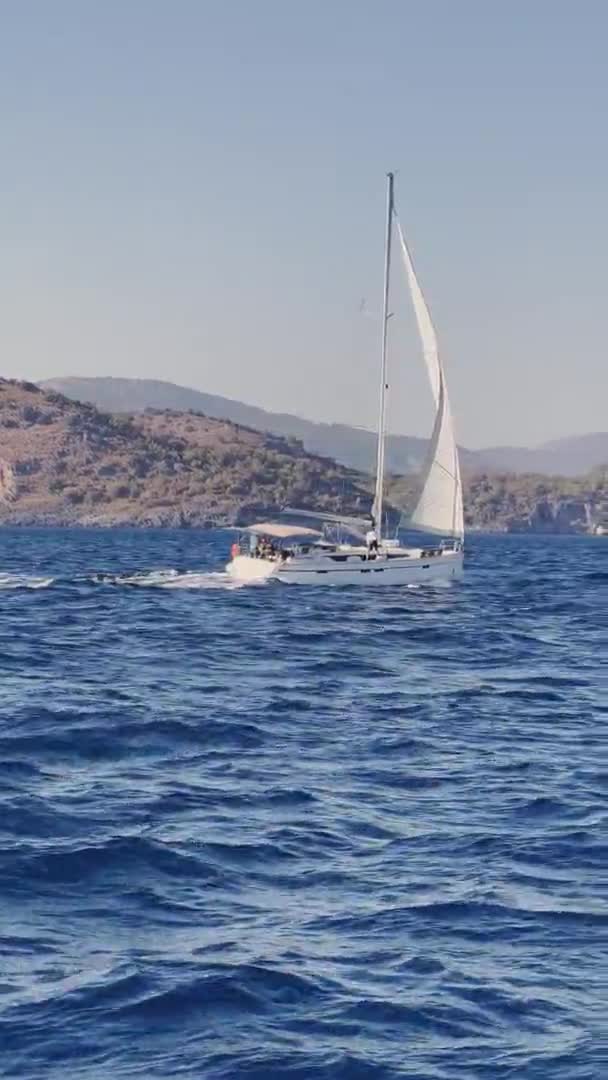 Turcja, Fethiye, 03 października 2021: Malownicza zatoka Sarsali, w pobliżu jednej z wielu wysp w pobliżu Marmaris, uczestnicy regat żaglowych na łodzi, góry na tle — Wideo stockowe