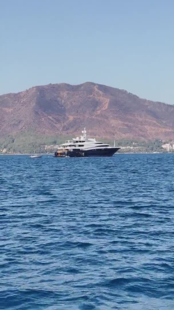 Le méga yacht de luxe amarré près du littoral dans la baie pittoresque de près d'une des nombreuses îles près de Marmaris, des pentes avec des arbres verts, des montagnes en arrière-plan — Video