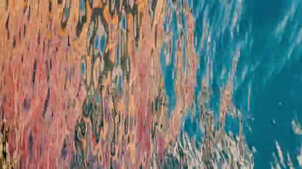 Vertikální záběry barevného odrazu desky obrovského člunu na vodě, malé vlny, modrá voda ve zpomaleném pohybu — Stock video