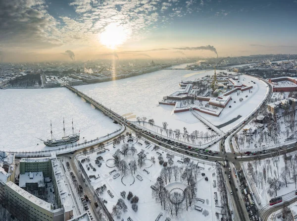 Ponto de vista drone do inverno São Petersburgo ao pôr do sol, rio Neva congelado, vapor sobre a cidade, fortaleza de Peter e Paul, tráfego de carros na ponte Trinity, colunas rostrais, ponte levadiça do palácio, vista panorâmica — Fotografia de Stock