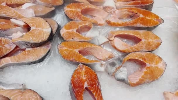 Close up footage of freshest pieces of salmon lie on crushed ice on the counter, there is cold steam, juicy color of fish, pieces of fish shine in the light — Vídeo de Stock