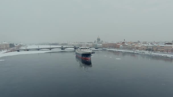 Russia, St. Petersburg, 07 December 2021: Slow motion footage of winter view of St. Petersburg at snow storm, frozen Neva river, huge ship, Isaac cathedral, car traffic on Blagoveshenskiy bridge — Stock Video