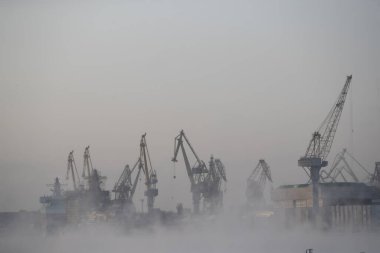 Nükleer buz kırıcıların inşası, soğuk bir kış gününde Baltık tersanesinin vinçleri, Neva nehrinin üzerinde buhar, nehrin pürüzsüz yüzeyi.