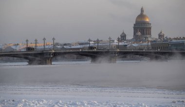Soğuk bir günde St. Petersburg 'un panoramik manzarası, arka planda Isaac katedrali ve Blagoveshenskiy köprüsü, donmuş Neva nehri üzerinde buhar, deniz kuvvetleri binası.