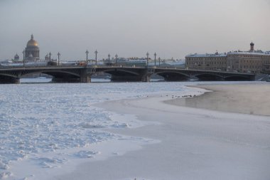 Soğuk bir günde St. Petersburg 'un panoramik manzarası, arka planda Isaac katedrali ve Blagoveshenskiy köprüsü, donmuş Neva nehri üzerinde buhar, deniz kuvvetleri binası.