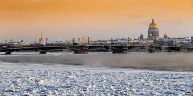 Gün batımında St. Petersburg 'un panoramik manzarası, arka planda Isaac Katedrali ve Blagoveshenskiy köprüsü, donmuş Neva nehri üzerinde buhar, turuncu renkli gökyüzü