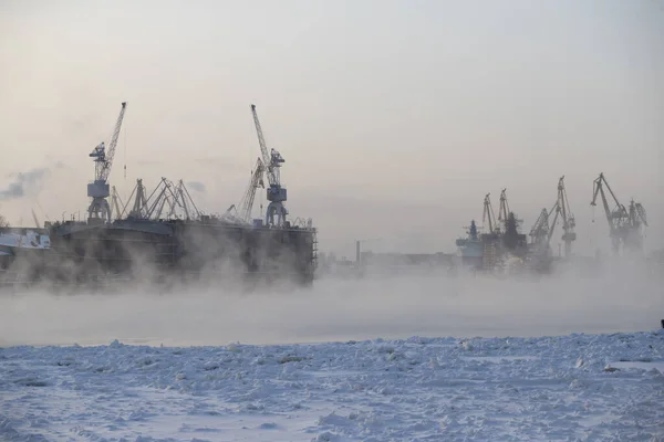 Nükleer buz kırıcıların inşası, soğuk bir kış gününde Baltık tersanesinin vinçleri, Neva nehrinin üzerinde buhar, nehrin pürüzsüz yüzeyi. — Stok fotoğraf