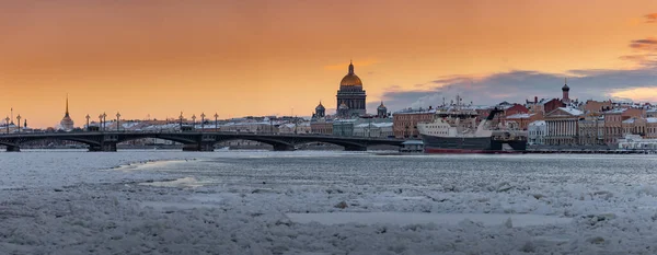 Vista panorâmica de inverno de São Petersburgo ao pôr do sol, catedral de Isaac e ponte de Blagoveshenskiy no fundo, vapor sobre o rio Neva congelado, navio enorme atracado perto de aterro, céu de cor laranja — Fotografia de Stock