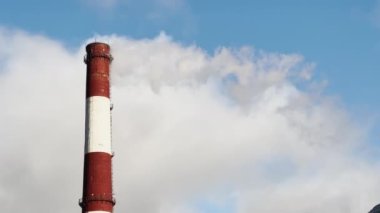 Kış boyunca bir termik santralin borularından çıkan buhar şehir, mavi gökyüzü ve güneş