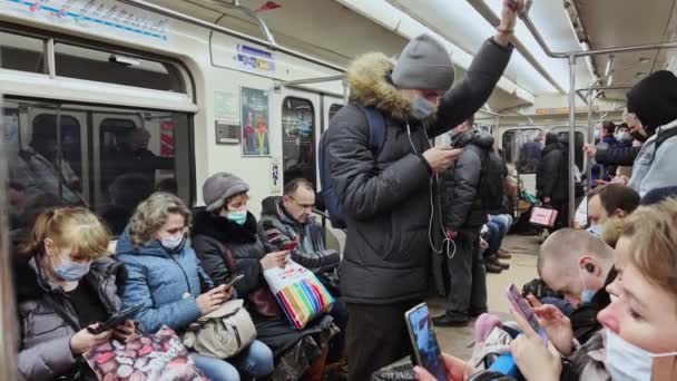 Россия, Санкт-Петербург, 28 декабря 2021 года: вагон метро вечером во время пандемии ковид-19 во всем мире, все медицинские маски, хмурящиеся люди похоронены в смартфонах, кто-то спит или играет — стоковое видео