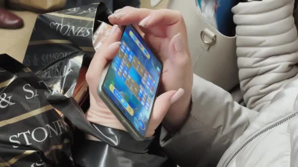 Russie, Saint-Pétersbourg, 28 décembre 2021 : Une femme joue à un jeu sur un smartphone, touche l'écran et le presse, elle va dans le métro, elle s'assoit avec des paquets sur ses genoux, pas de visage, bonne manucure — Video