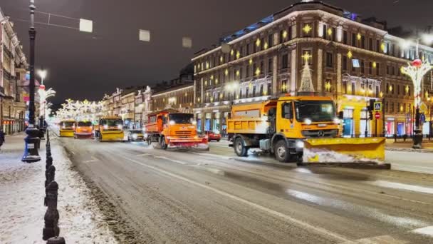 Rusya, St. Petersburg, 01 Ocak 2022: Birkaç kar küreme aracı aynı anda ana caddeyi temizliyor, şehrin yeni yıl için parlak şenlikli dekorasyonları, kamu hizmetleri çalışmaları — Stok video