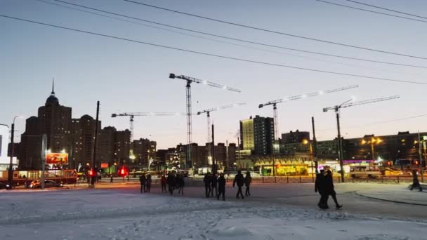 Rusia, San Petersburgo, 31 de diciembre 202: Los peatones cruzan la intersección, el tráfico de automóviles, varias grúas de construcción contra el telón de fondo de un cielo al atardecer, señales multicolores en el edificio — Vídeos de Stock