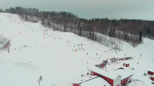Drone vista por cable en la estación de esquí. Ascensor de telesilla que transporta esquiadores y snowboarders en la ladera nevada del invierno en la montaña durante el fin de semana, dron volando sobre la ladera nevada — Vídeo de stock