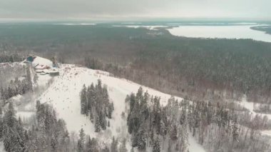 Drone view on cable way in ski resort. Ski lift elevator transporting skiers and snowboarders on snowy winter slope at mountain at weekend, drone flying over snowy slope