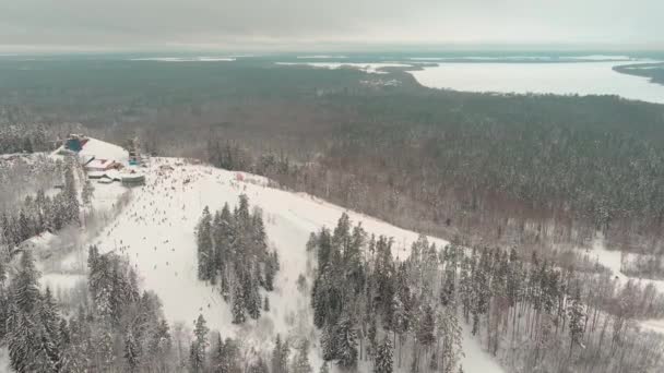 Drone view on cable way in ski resort. Ski lift elevator transporting skiers and snowboarders on snowy winter slope at mountain at weekend, drone flying over snowy slope — Vídeo de Stock