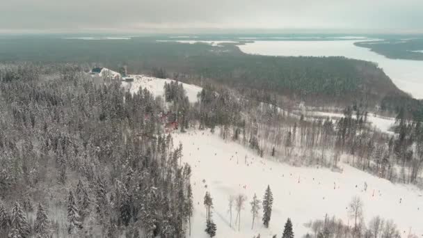 Drone view on cable way in ski resort. Ski lift elevator transporting skiers and snowboarders on snowy winter slope at mountain at weekend, drone flying over snowy slope — Stok video