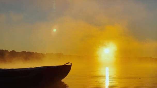 Kayaker flotte sur l'eau calme à travers le brouillard matinal au-dessus de l'eau au lever du soleil, la silhouette d'un homme avec une pagaie sur un kayak, la couleur dorée de l'eau, l'eau chaude et l'air froid, la lumière magique — Video