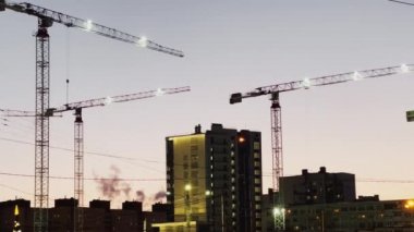 Rusya, St.Petersburg, 31 Aralık 202: Kavşaktan geçen yayalar, araba trafiği, günbatımında gökyüzünün arka planına karşı çok sayıda inşaat vinci, bina üzerinde çok renkli tabelalar