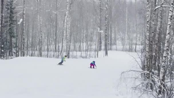 Russia, St. Petersburg, 03 January 2022: Young people on skis and snowboards on the slopes of the ski resort on the weekend, colorful overalls of athletes on a snowy winter day — стокове відео