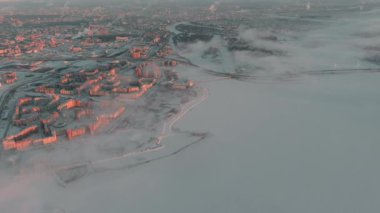 Russia, St. Petersburg, 08 January 2022: Snow-covered stadium Gazprom Arena near the expressway on a winter frosty evening, view from drone to the embankment