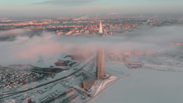 Россия, Санкт-Петербург, 08 января 2022 года: Небоскрёб Лахтинского центра в зимний мороз на закате, будущая главная строительная нефтяная компания "Газпром", беспилотник неподвижен, над зданием плавают облака — стоковое видео