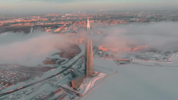 Oroszország, Szentpétervár, 2022. január 08.: Lakhta center felhőkarcoló télen, naplementekor, a Gazprom fő építőolajvállalat, drón repül az épülethez, felhők lebegnek az épület felett — Stock videók