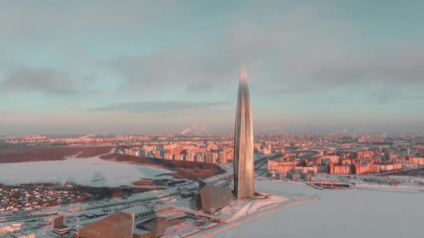 Rusia, St. Petersburg, 08 Januari 2022: pencakar langit pusat Lakhta dalam dingin dingin saat matahari terbenam, bangunan utama masa depan kantor perusahaan minyak Gazprom, drone memanjat seluruh bangunan — Stok Video