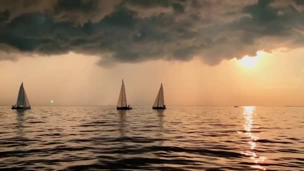 Alguns veleiros em um mar ao pôr do sol, reflexo mágico do sol, caminho do sol, o céu da cor rosa, o céu escuro tempestade, nuvem de chuva no horizonte, água escura calma — Vídeo de Stock