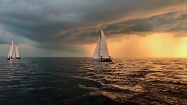 Russia, San Pietroburgo, 21 giugno 2019: Poche barche a vela in un mare al tramonto, regata velica, il cielo di colore rosa, il cielo di tempesta oscuro, nuvole di pioggia all'orizzonte, acque scure calme, riflesso magico del sole — Video Stock