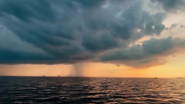 Den ensamma segelbåten i en lista går till sjöss vid solnedgången, himlen av rosa färg, mörkret storm himlen, regn moln i horisonten, lugnt vatten, magi sol reflektion, sol väg — Stockvideo