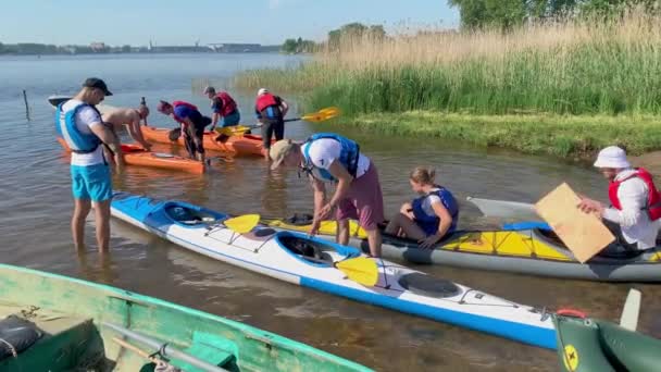 Russia, St. Petersburg, 08 June 2019: People are preparing to participate in a city rowing championship of kayaking, athletes prepare oars and life jackets, smear with sunscreen, sharing experiences — стокове відео