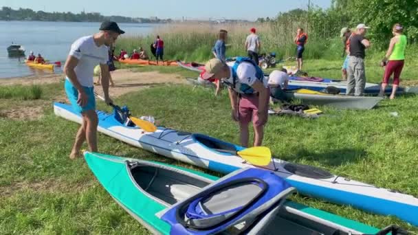 Russia, St. Petersburg, 08 June 2019: People are preparing to participate in a city rowing championship of kayaking, athletes prepare oars and life jackets, smear with sunscreen, sharing experiences — стоковое видео