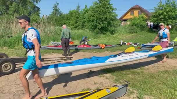 Russia, St. Petersburg, 08 June 2019: People are preparing to participate in a city rowing championship of kayaking, athletes prepare oars and life jackets, smear with sunscreen, sharing experiences — Stock video