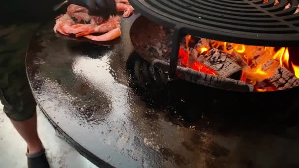 夏天，一只手拿着橡胶手套，在炽热的铁皮表面，新鲜的海鲜上放着大虾，用炽热的火焰在火盆上烤新鲜的国王虾，这个过程的镜头非常逼真, — 图库视频影像