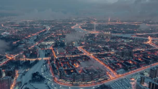 Aerial winter cityscape of St. Petersburg - Russia, drone flies over huge housing estates at evening, construction cranes, night illumination, night cityscape, clouds float below drone — Stock Video