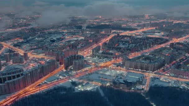 Zimowy pejzaż miasta Sankt Petersburga - Rosja, człon przelatuje nad ogromnymi osiedlami w godzinach wieczornych, żurawie budowlane, oświetlenie nocne, nocny pejzaż miasta, chmury unoszą się poniżej drona — Wideo stockowe