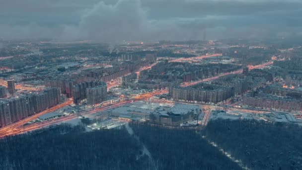 Paisagem urbana de inverno aéreo de São Petersburgo - Rússia, drone voa sobre enormes propriedades habitacionais à noite, guindastes de construção, iluminação noturna, paisagem urbana noturna, nuvens flutuam abaixo do drone — Vídeo de Stock