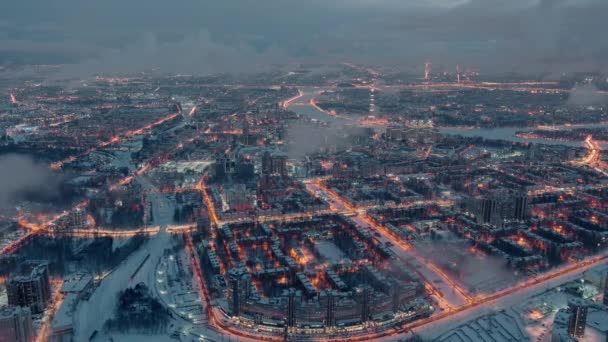 Zimowy pejzaż miasta Sankt Petersburga - Rosja, człon przelatuje nad ogromnymi osiedlami w godzinach wieczornych, żurawie budowlane, oświetlenie nocne, nocny pejzaż miasta, chmury unoszą się poniżej drona — Wideo stockowe