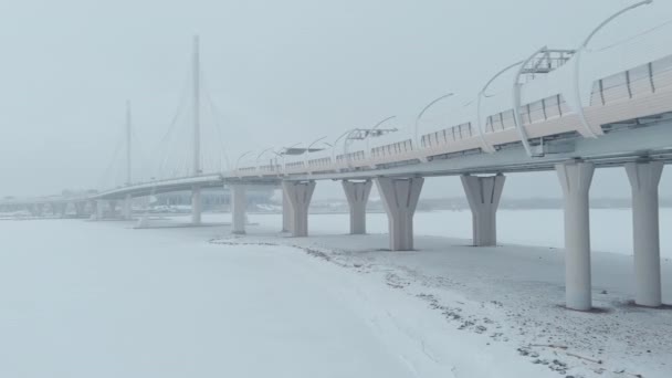 A drón végigrepül a kábeles hídon hóviharban, autópályán, hóviharban. — Stock videók