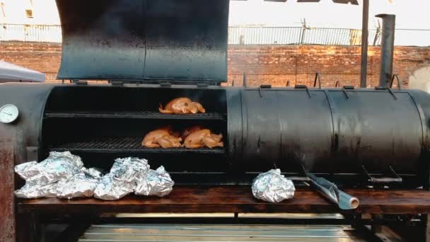 Turkey carcasses are smoked in a special grill smokehouse in the form of a barrel, a roll of foil for packaging the finished dish and sale — Stock Video