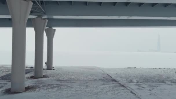 Россия, Санкт-Петербург, 22 января 2022 года: Беспилотник пролетает по канатному мосту в снежную бурю, небоскреб "Лахта-центр" нефтяной компании "Газпром" на заднем плане, шоссе, метель — стоковое видео