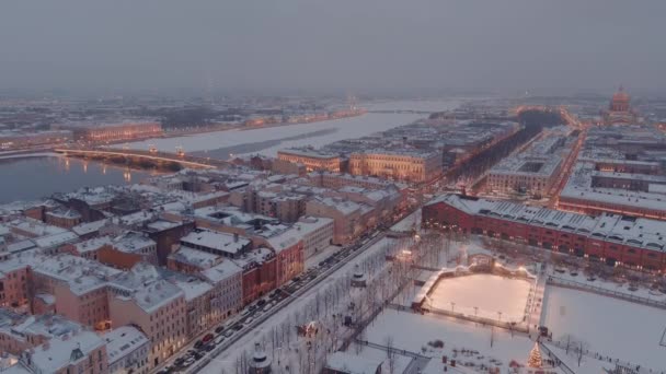 Flygdrönare utsikt över centrala distriktet med landmärken i Sankt Petersburg i en snöig vinterkväll, ön New Holland, natt belysning av byggnader natt stadsbild, utomhus skridskobana — Stockvideo